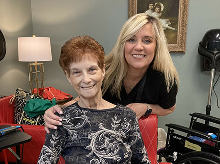 Nurse with resident, both smiling into the camera